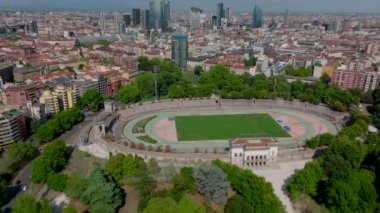 Kamu parkının yüksek açılı manzarası ve tarihi atletizm stadyumu. Yukarı doğru eğilince şehir merkezindeki yüksek katlı ofis binalarının manzarası ortaya çıkıyor. Milano, İtalya.