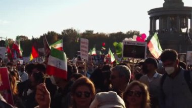 İranlılar ve destekçileri büyük bir miting düzenliyor. İran bayrakları ve sancakları olan insanlar. Berlin, Almanya.