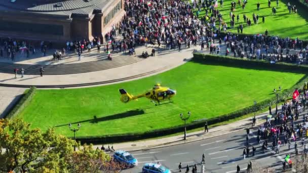 広場の緑豊かな緑の領域に救助ヘリコプターの着陸 抗議する人々の群衆 ドイツ ベルリン — ストック動画