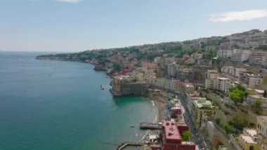 Turizm merkezinin panoraması. Suyun üzerindeki dik yamaçlarda oteller ve saraylar ve kumsalda güneşli bir günün tadını çıkaran insanlar. Napoli, İtalya.