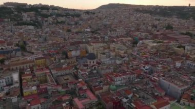 Günbatımında ünlü şehrin tarihi merkezinin üzerinde ilerliyorlar. Eski binalar ve turistleri çeken değerli yerler. Napoli, İtalya.