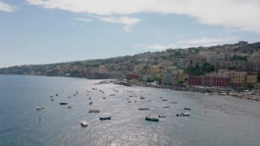 Deniz kıyısında sığ sulara demirlenmiş teknelerin sinematik görüntüleri. Lüks oteller ve turistik yerlerde denizin yukarısındaki tarihi saraylar. Napoli, İtalya.