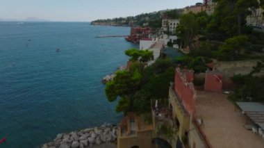 Seyahat rotasında deniz kıyısının üzerinde uç. Posillipo ilçesinin yukarısındaki bayırda renkli binalar. Napoli, İtalya.