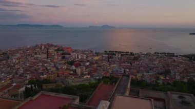 Alacakaranlıkta deniz kıyısındaki şehir merkezinin hava panoramik manzarası. Geriye doğru, tarihi bir manastır olan Chiostro Grande 'yi ortaya çıkardı. Napoli, İtalya.
