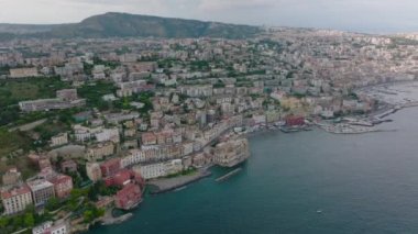 Deniz kıyısındaki şehrin havadan panoramik görüntüsü. Su ve şehir limanının yukarısındaki yamaçta büyük binaları olan lüks turistik bir yer. Napoli, İtalya.