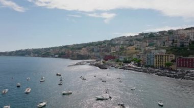 Akdeniz turizm merkezindeki deniz kıyısının havadan görünüşü. Sığ sulara demirlenmiş teknelerin geriye dönük görüntüsü. Renkli binalar ve saraylar. Napoli, İtalya.