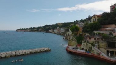 Deniz kıyısı turistik bölgede. Geriye doğru, insanların bankadaki su sporlarından ve renkli binalardan hoşlandıklarını gösteriyor. Napoli, İtalya.