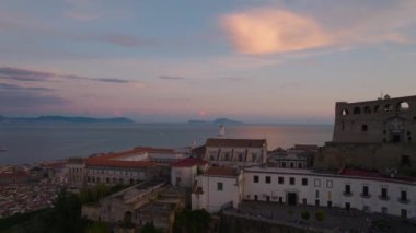 Tarihsel dini simgelerin üzerinde uçar ve Napoli Körfezi 'ndeki kıyı kenti semtini gözler önüne serer. Gün batımında gökyüzündeki bulutu yansıtan su yüzeyi. Napoli, İtalya.