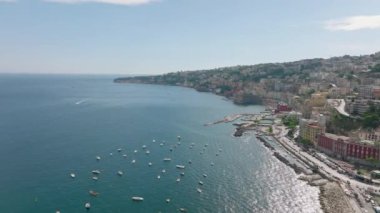 Yaz yolculuklarının hava panoramik görüntüleri. Tekneler kıyıda ve kasaba limanında sığ sularda demirlemişti. Su boyunca renkli binalar. Napoli, İtalya.