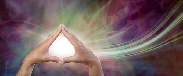 Creating a healing energy flow destined for you - male healer sending high frequency healing energy through the ether against a beautiful ethereal green magenta background with copy space