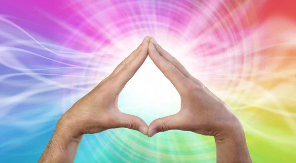 Working with rainbow vortex Healing Energy - male hands making a triangle shape on a rotating multicoloured energy field background with copy space