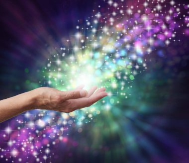 Sihirli Enerji İyileştirici Eller Konsepti - parlak ve bokeh arkaplan, ortasında bir kadın avucu ve ince spiral içinden akan çok renkli bir enerji akışı. 