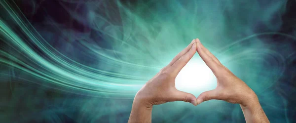 Healer attracting scalar energy with palm chakras - male hands touching fingertips together with a white orb between against a green navy blue energy field and a stream of energy flowing in