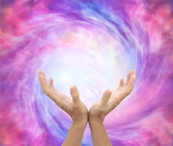 Healer sensing awesome vortexing energy field - female hands reaching into a spiralling pink energy field with space for message