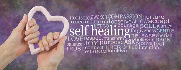 Чувствуемое сердцем самоисцеляющееся слово "облачный фон" - женские руки, держащие розовую раму в форме сердца рядом с самоисцеляющимся словооблаком на деревенском многоцветном фоне