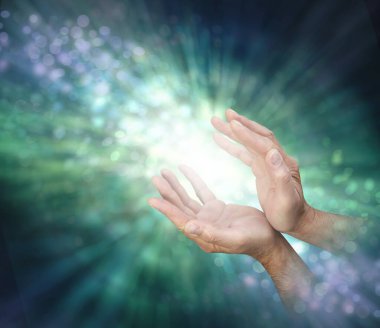 Channelling healing energy to where it is needed - male cupped hands with light between and a stream of outward spiralling green  energy against a bokeh background and copy space clipart