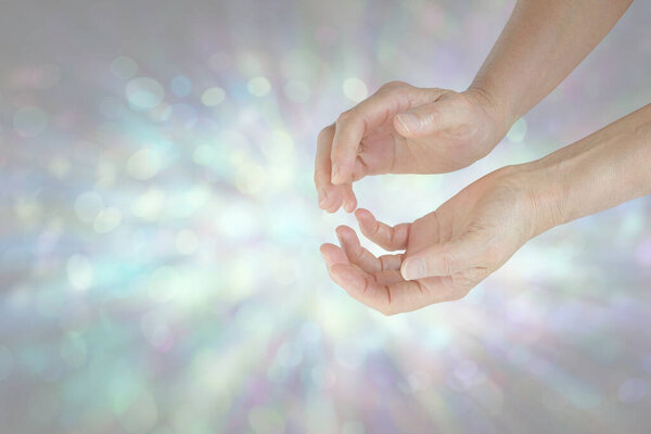 Скромная исцеляющая энергия, исходящая из обхваченных руками - женские руки, прижатые к бледному мягкому всплеску боке света и пространства для текстовых сообщений