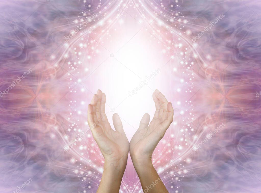 Sensing high frequency love and light healing energy - open female hands with white light between against beautiful purple pink peach sparkling energy field background and copy space 