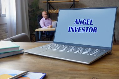 Bilgisayarında yazı olan ANGEL INVESTOR ile ilgili bir iş konsepti. İş adamı arka planda belgelerle çalışıyor..