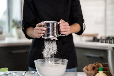 Mutfakta yemek pişirmek. Un, şeffaf bir kâseye karıştırılıyor.
