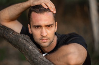 Ağaç dalına yaslanmış genç bir adamın portresi.