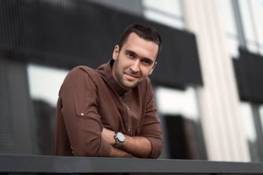Tıraşsız, kahverengi gömlekli ve elleri çalıntı genç bir adamın portresi.