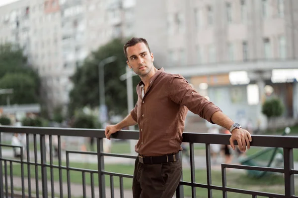 Şehir caddesinde kahverengi gömlekli, tıraşsız, genç bir adamın portresi.