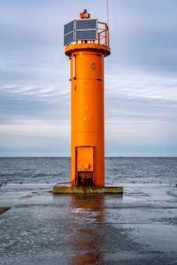 Mangalsala 'nın sonundaki turuncu deniz feneri ya da Letonya' nın Riga kentinde Daugava nehrinin Baltık Denizi 'ne aktığı doğu iskelesi. Kış fırtınası, soğuk hava, buz ve kar.