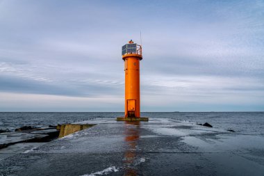 Mangalsala 'nın sonundaki turuncu deniz feneri ya da Letonya' nın Riga kentinde Daugava nehrinin Baltık Denizi 'ne aktığı doğu iskelesi. Kış fırtınası, soğuk hava, buz ve kar.