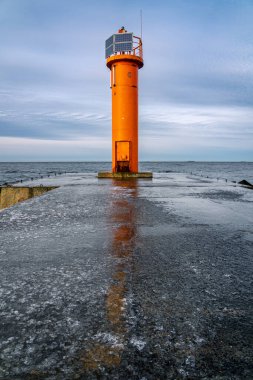 Mangalsala 'nın sonundaki turuncu deniz feneri ya da Letonya' nın Riga kentinde Daugava nehrinin Baltık Denizi 'ne aktığı doğu iskelesi. Kış fırtınası, soğuk hava, buz ve kar.
