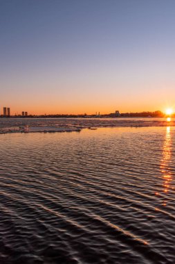 Riga Limanı 'nda sakin bir kış günü. Kısmen donmuş Daugava nehri ve arka planda Z kuleleri olan sanayi bölgesi.