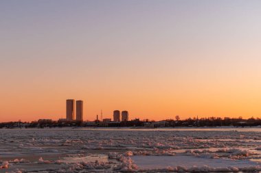 Riga Limanı 'nda sakin bir kış günü. Kısmen donmuş Daugava nehri ve arka planda Z kuleleri olan sanayi bölgesi.