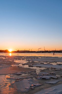 Riga Limanı 'nda sakin bir kış günü. Kısmen donmuş Daugava nehri ve arka planda Z kuleleri olan sanayi bölgesi.