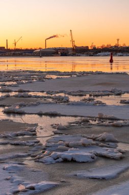 Riga Limanı 'nda sakin bir kış günü. Kısmen donmuş Daugava nehri ve arka planda Z kuleleri olan sanayi bölgesi.