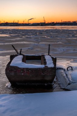 Riga Limanı 'nda sakin bir kış günü. Kısmen donmuş Daugava nehri ve arka planda Z kuleleri olan sanayi bölgesi.