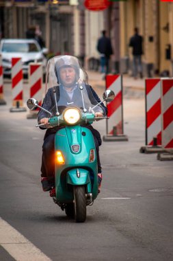 Riga, Letonya sokaklarında Vespa scooter kullanan bir adam.