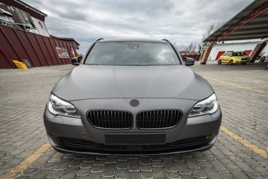 Predatory car headlight with blue lights and hood of powerful grey blue car sports car with matte grey paint and wheel