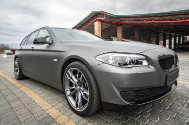 Predatory car headlight with blue lights and hood of powerful grey blue car sports car with matte grey paint and wheel