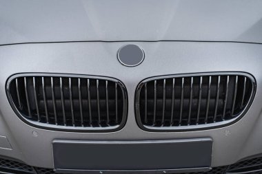 Predatory car headlight with blue lights and hood of powerful grey blue car sports car with matte grey paint and wheel