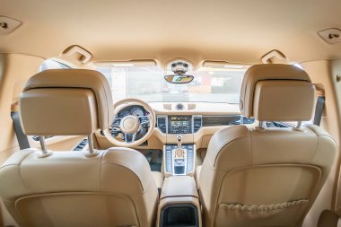 Araç içi lüks. Bej konforlu koltuklar, direksiyon, gösterge paneli, iklim kontrolü, hız göstergesi, ekran, ahşap süsleme ışığı