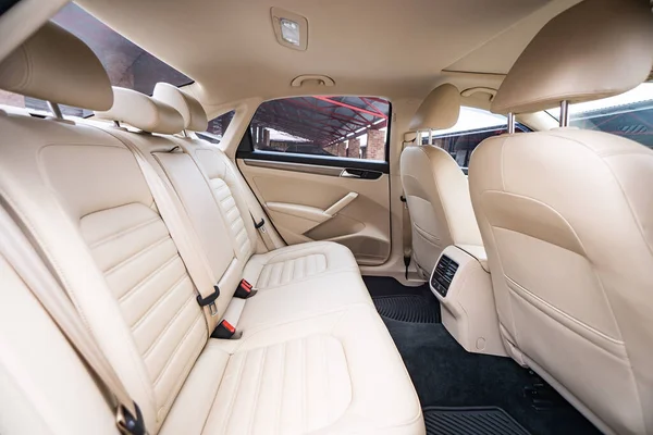 Araç içi lüks. Bej konforlu koltuklar, direksiyon, gösterge paneli, iklim kontrolü, hız göstergesi, ekran, ahşap süsleme ışığı
