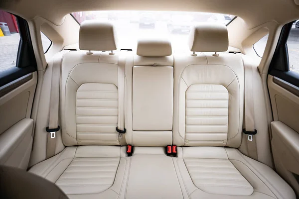 Araç içi lüks. Bej konforlu koltuklar, direksiyon, gösterge paneli, iklim kontrolü, hız göstergesi, ekran, ahşap süsleme ışığı