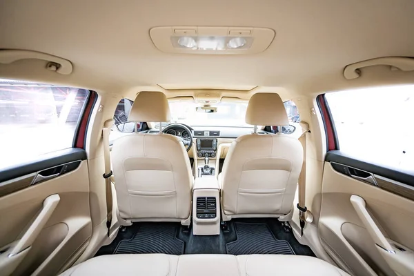 Araç içi lüks. Bej konforlu koltuklar, direksiyon, gösterge paneli, iklim kontrolü, hız göstergesi, ekran, ahşap süsleme ışığı