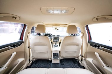 Araç içi lüks. Bej konforlu koltuklar, direksiyon, gösterge paneli, iklim kontrolü, hız göstergesi, ekran, ahşap süsleme ışığı