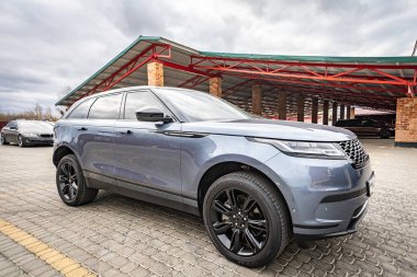 Predatory car headlight with blue lights and hood of powerful grey blue car sports car with matte grey paint and wheel