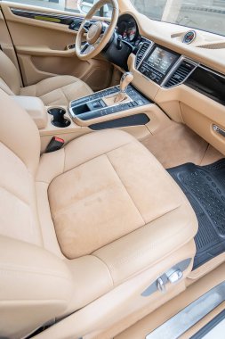 Araç içi lüks. Bej konforlu koltuklar, direksiyon, gösterge paneli, iklim kontrolü, hız göstergesi, ekran, ahşap süsleme ışığı