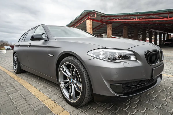 Predatory car headlight with blue lights and hood of powerful grey blue car sports car with matte grey paint and wheel