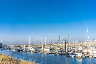 IJmuiden, Hollanda - 29 Mart 2022: Günbatımına yakın güneşli bir günde tekneli kuzey denizi ve marina.
