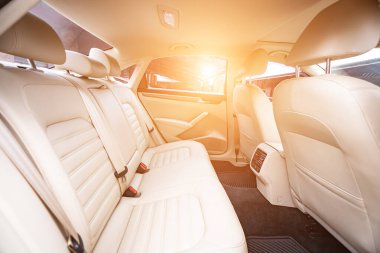 Araç içi lüks. Bej konforlu koltuklar, direksiyon, gösterge paneli, iklim kontrolü, hız göstergesi, ekran, ahşap süsleme ışığı