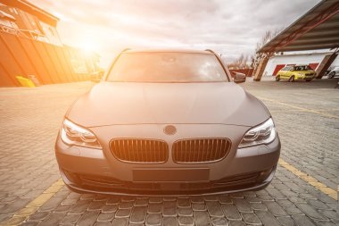 Predatory car headlight with blue lights and hood of powerful grey blue car sports car with matte grey paint and wheel